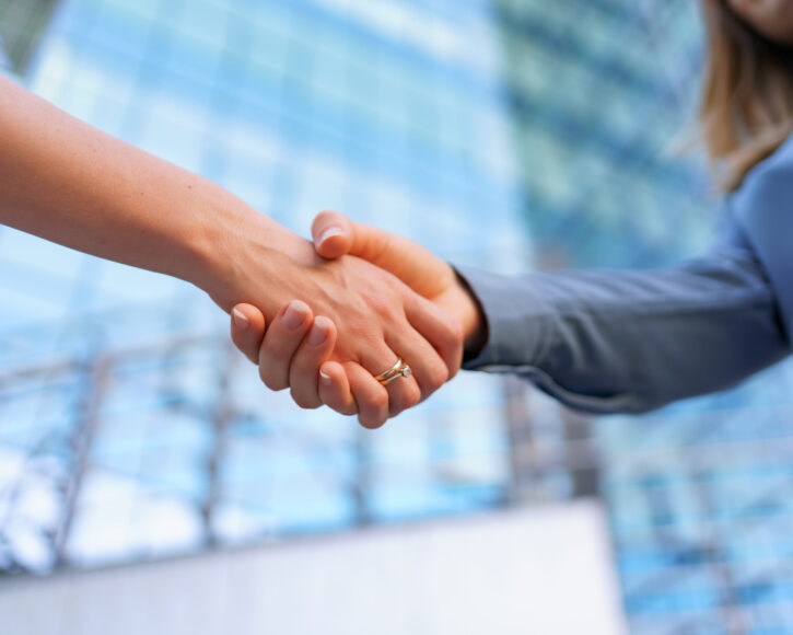 Woman handshaking outdoors over modern glass business building background, close-up picture
